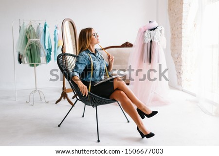 Attractive female fashion designer is working in her workshop. Stylish woman in process of creating new clothes collection.