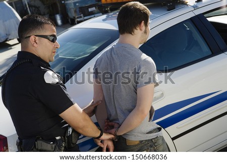 Police Officer Arresting Young Man Royalty-Free Stock Photo #150668036