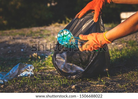 Garbage bottles picked up and thown into a trash bag. Plastic and food waste concept. Clean planet Earth, collect garbage, avoid pollution, save environment.