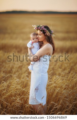 mom in a white dress holds a small child
