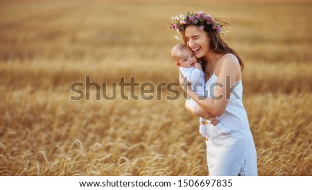 mom in a white dress holds a small child