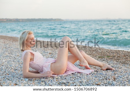 Portrait of a fashionable beautiful blonde woman on the beach by the sea