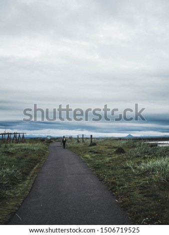 A lone traveler on Sculpture and Shore Walk path in Grotta area with mountains seen on the horizon. 