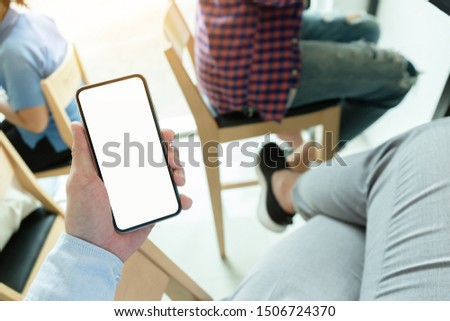 Mockup image blank white screen cell phone.men hand holding texting using mobile on desk at coffee shop or office background empty space for advertise text. contact people communication,technology 