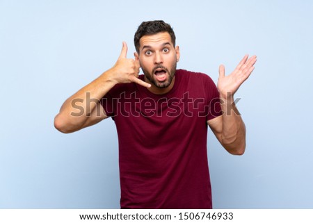 Handsome man over isolated blue background making phone gesture and doubting