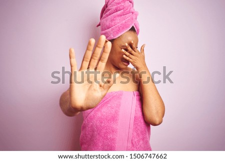African american woman wearing shower towel after bath over pink isolated background covering eyes with hands and doing stop gesture with sad and fear expression. Embarrassed and negative concept.