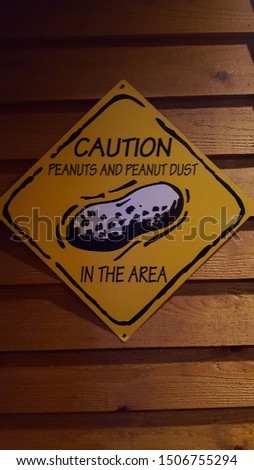 Sign board saying "Caution peanuts and peanut dust in the area".