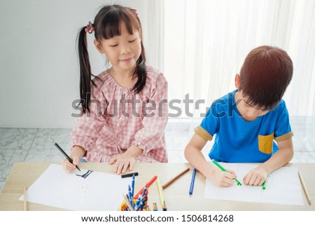 A boy and girl are drawing picture on paper at school 