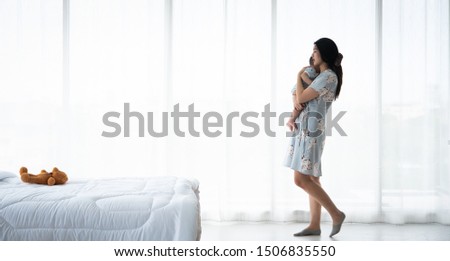 Mother soothe her son in white bed room by the window