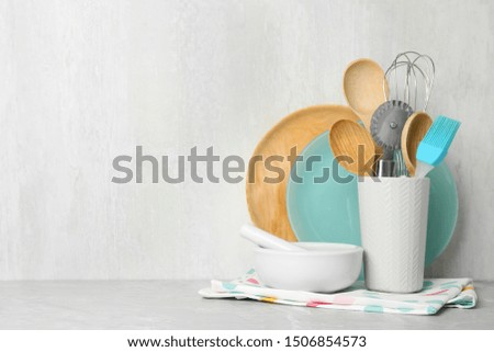 Different kitchen utensils on grey table against light background. Space for text
