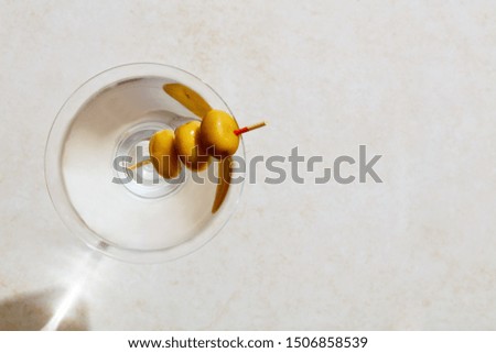 Glass of dry martini with olives under hard summer sunlight. Overhead view with copy space.