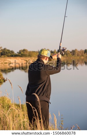 A fisherman is fishing on a spinning near the river, using high-quality gear and good bait, the catch of trophies will be excellent. Vacations and outdoor sports with active leisure