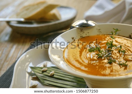Roasted pumpkin cream soup served with bread on the restaurant table. Exquisite dish. Creative restaurant meal. Fine dining concept.