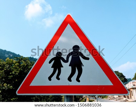 A sign board on a mountainous road which says that parents must keep their children close to them at all times. 