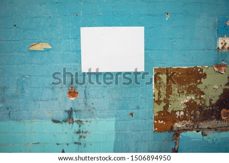 Close up of a blank sign hanging on a blue brick wall