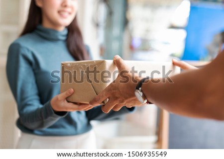Woman receiving parcel from hands delivery man at the door. Royalty-Free Stock Photo #1506935549