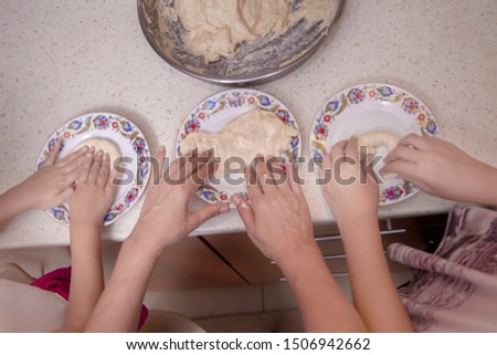 Kids and mother hands doing donuts in dough