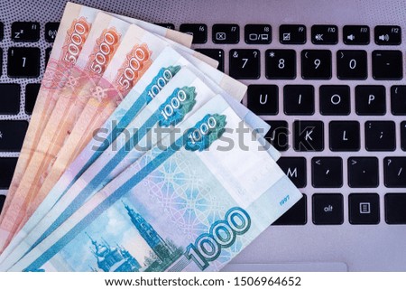 A pack of Russian rubles lies on the laptop keyboard. Top view.