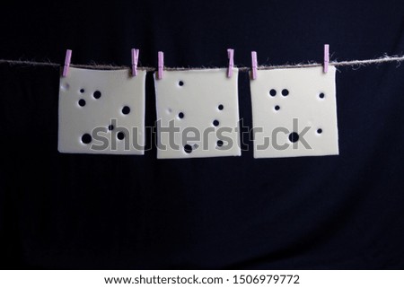 three pieces,slice of cheese on a rope  with clothespins black background