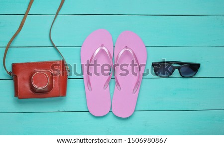 The concept of vacation on the beach, tourism. Summer traveler background. Flip flops, retro camera, sunglasses on a blue wooden background. Top view. Flat lay