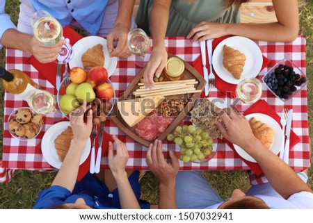 Young people having picnic at table in park, top view