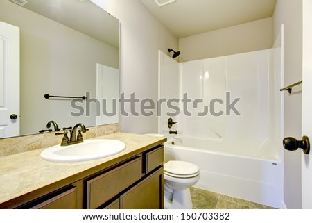 New home bathroom  interior with shower and bath combination, wood cabinet and toilet.