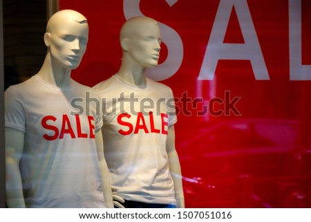 Mannequins in a window of a clothing store, sale inscriptions