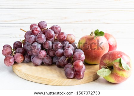Creative composition with fresh ripe grapes and juicy tasty apple on the wooden tray. Healthy and tasty food concept. Autumn harvest concept.