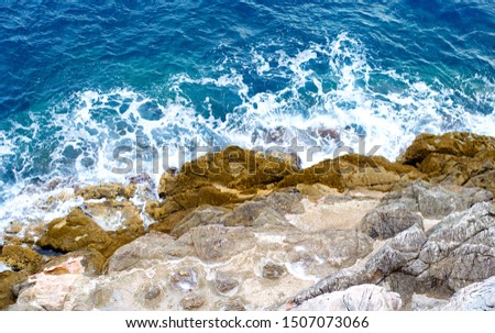 blue sea and rocks covered by green moss