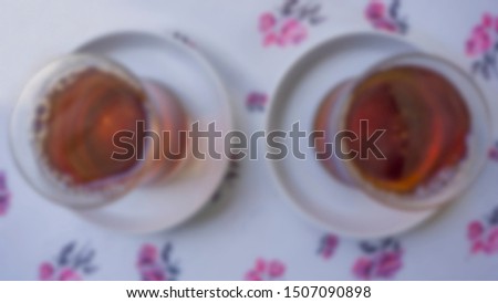 A nice and pleasant conversation with two Turkish traditional brewed teas in the afternoon. Two tea glasses on the patterned table. Afternoon tea. Blurred, defocused photo.