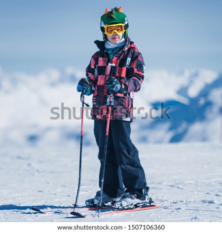 Young male skier in colorful outfit on top of mountain ski resort