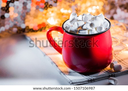 Red mug with hot chocolate and marshmallows and lights. Christmas concept.