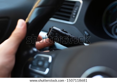 Close-up of male hand, presses signal switch button in the car.