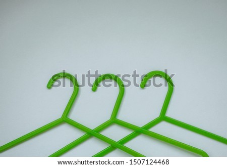 Three green plastic hangers for adults and children's clothing on white background with space for text. The concept of shopping, sales, nothing to wear, children's clothing
