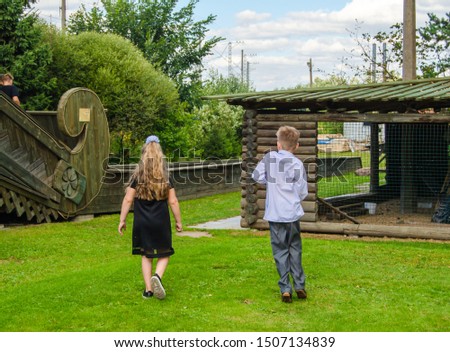 little girl and boy are walking in the park on a sunny day
