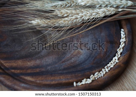 Ears of wheat and grains on dark wooden board, selective focus
