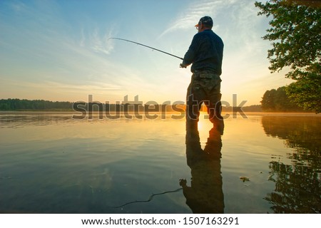 Angler catching the fish in the lake during sunrise
 Royalty-Free Stock Photo #1507163291