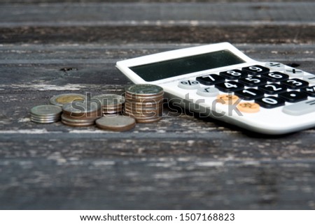Calculator with coin stack on old wooden floor background. Concept for business investment and accounting