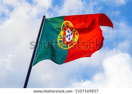 Portuguese flag waving in front of a blue sky