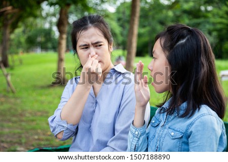 Asian daughter child girl checking breath with her hand,teen girl horrible bad breath,foul mouth,mother closing her nose,very bad smell,feeling stinks,facial expression,health care,halitosis concept Royalty-Free Stock Photo #1507188890