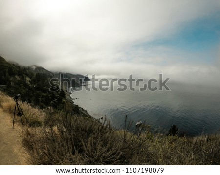 Stock photographer's camera on tripod pointing at landscape