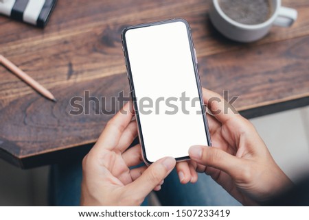 Mockup image blank white screen cell phone.men hand holding texting using mobile on desk at coffee shop. background empty space for advertise text. contact business,people communication,technology