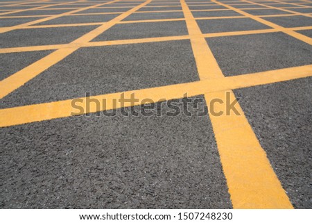 Low angle close-up of yellow asphalt cross grid on asphalt road