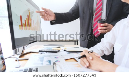 two young businessmen partner explaining information and pointing at report data discussing strategy agreement or contract at office, Teamwork, cooperation