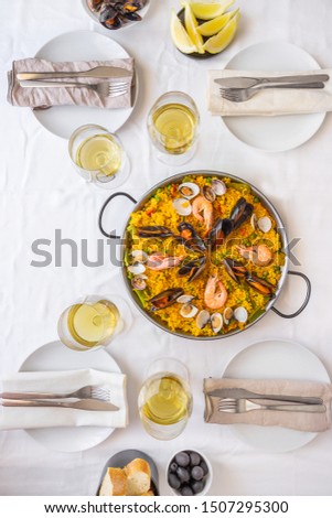 Table setting for friends meeting. Spanish paella for food friends. Top view lifestyle background.