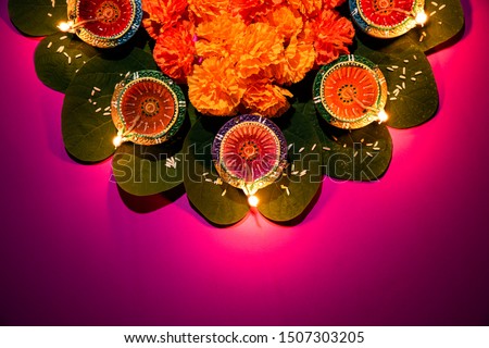 Happy Dussehra. Clay Diya lamps lit during Dussehra with yellow flowers, green leaf and rice on pink pastel background. Dussehra Indian Festival concept. Royalty-Free Stock Photo #1507303205