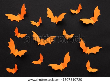 halloween  concept - orange paper bats flying over black background