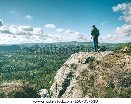 Man photographer taking picture of landscape when set tripod at mountain peak. Travel and hobbies concept.