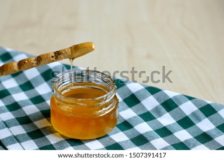 Breadstick or Italian grissini. Tasty grissini snack with honey on table with green gingham tablecloth. Food, harvest concept. 