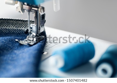 Sewing machine with denim and thread for sewing, close-up. The working process. Part of a sewing machine with blue cloth. Royalty-Free Stock Photo #1507401482